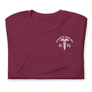 Folded maroon ICU nurse shirt with white ICU RN left-chest design.
