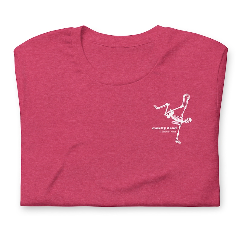 Puede incluir: Una camiseta rosa con un gr&aacute;fico de esqueleto blanco y el texto "mostly dead & slightly alive".