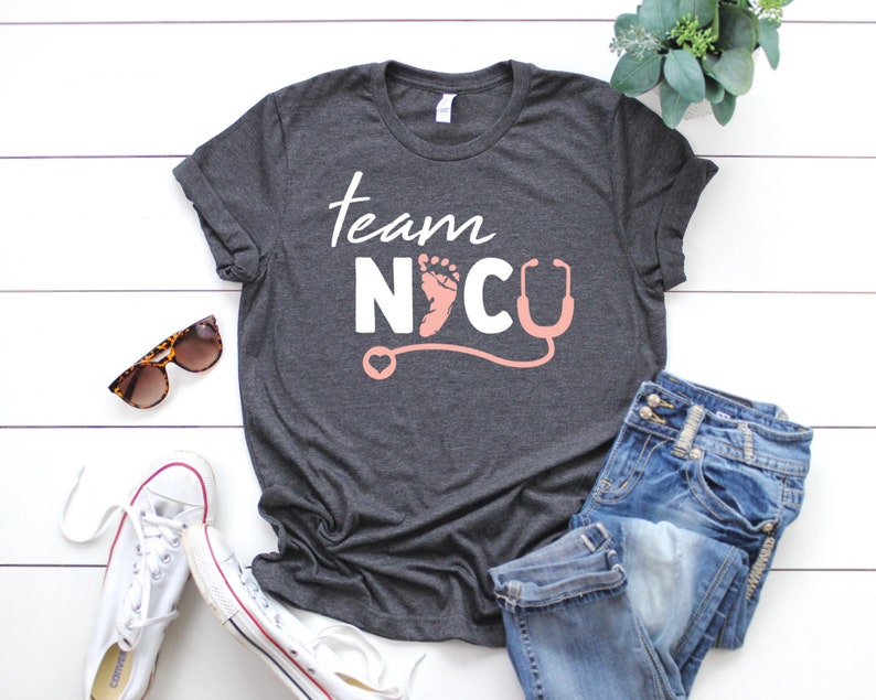 May include: Gray t-shirt with the text "Team NICU" in white with a pink footprint and stethoscope graphic.