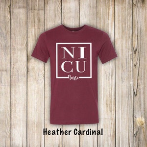 May include: A maroon t-shirt with a white square that says "NICU Nurse" in all caps.