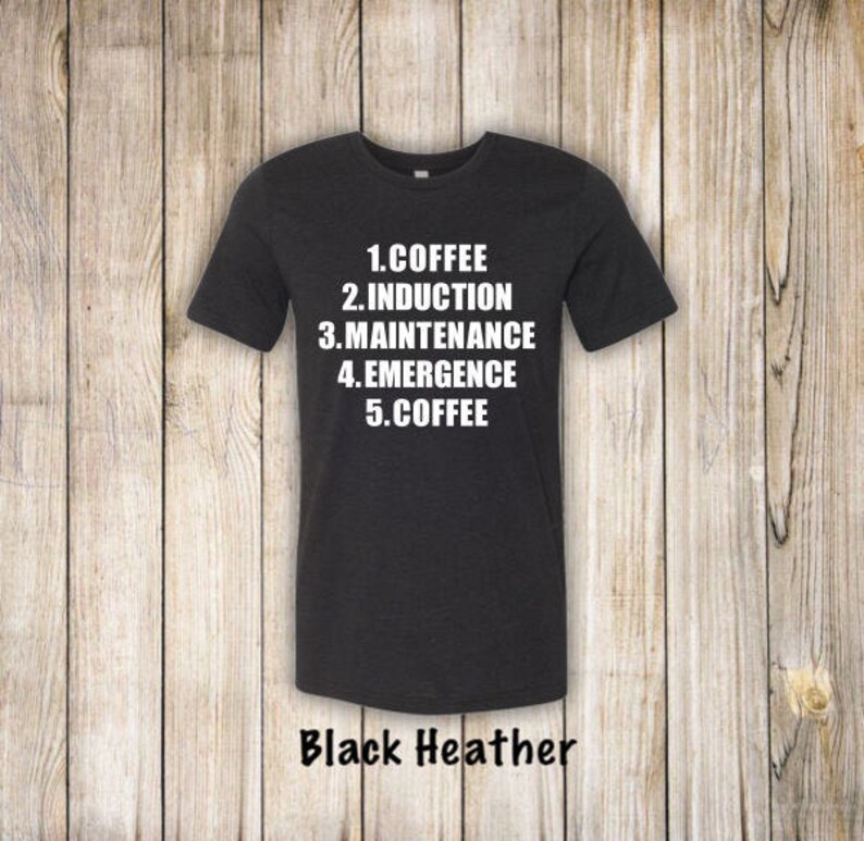 May include: A black heather t-shirt with white text that reads "1. Coffee 2. Induction 3. Maintenance 4. Emergence 5. Coffee".