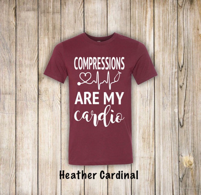 May include: A maroon t-shirt with white text that reads "COMPRESSIONS ARE MY cardio" with a stethoscope and a heart beat graphic.