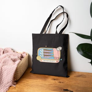 Black Tin Fish Society tote bag with vintage sardine illustration on minimal background