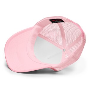 May include: Pink trucker hat with a mesh back. The hat has a small black label with the text "OTTO" on the back.