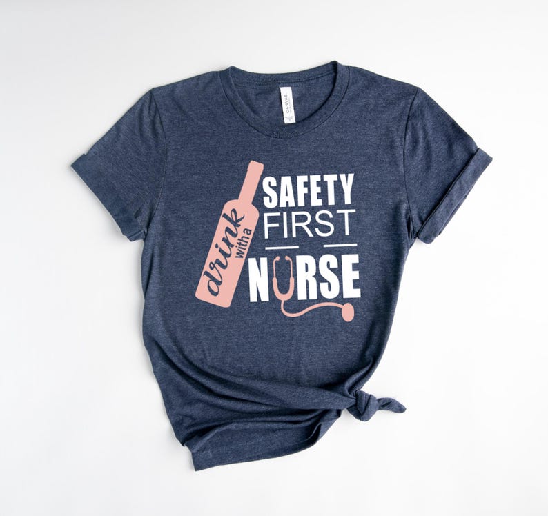 K&ouml;nnte beinhalten: Ein marineblaues T-Shirt mit einer pinkfarbenen Weinflaschengrafik und dem Text "drink with a nurse" und "safety first" in Wei&szlig;.