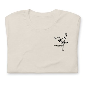 Puede incluir: Una camiseta beige con un gr&aacute;fico de esqueleto negro y el texto "mostly dead is slightly alive".