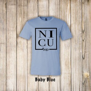 May include: A baby blue t-shirt with a black square that says "NICU Nurse" on it.