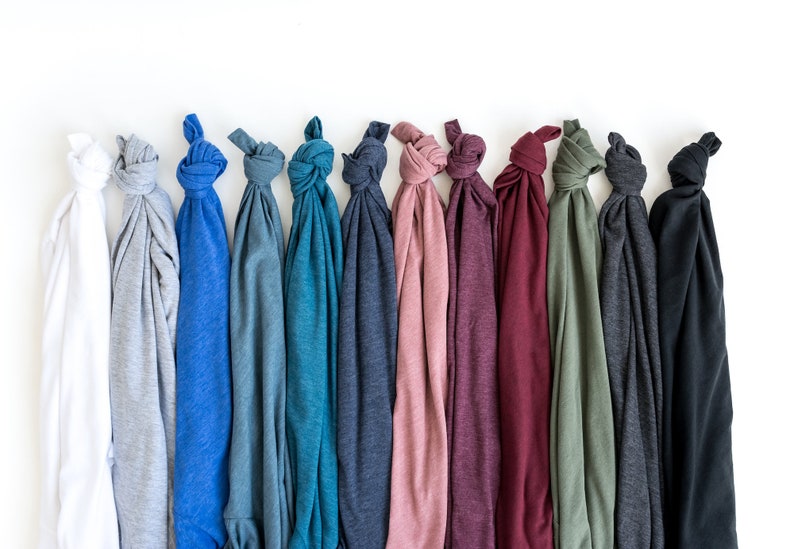 May include: A row of 12 t-shirts in various colors, including white, gray, blue, teal, navy, pink, burgundy, green, charcoal, and black. The t-shirts are folded and tied in a knot at the top.