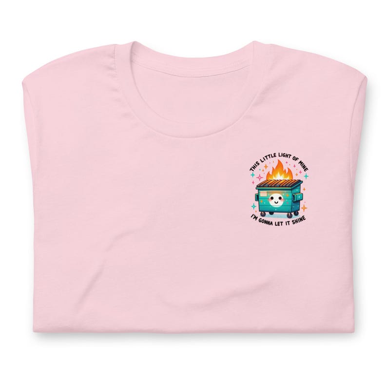 Puede incluir: Camiseta rosa con un gr&aacute;fico de un contenedor verde en llamas con el texto "This little light of mine, I'm gonna let it shine."