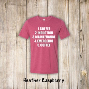 May include: Heather raspberry t-shirt with white text that reads "1. Coffee 2. Induction 3. Maintenance 4. Emergence 5. Coffee"