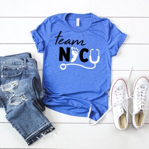 May include: A blue t-shirt with the text "Team NICU" in black lettering. A white footprint and a stethoscope are included in the design.