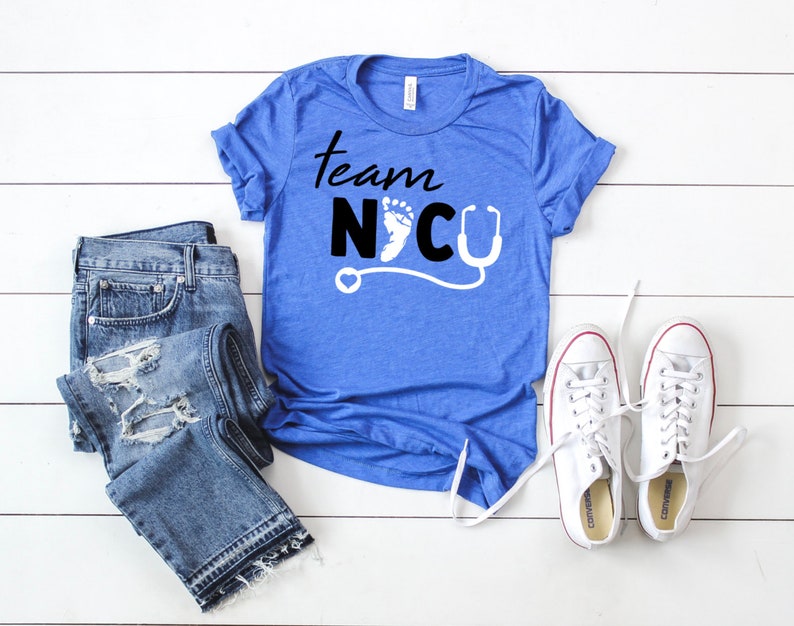 May include: A blue t-shirt with the text "Team NICU" in black lettering. A white footprint and a stethoscope are included in the design.