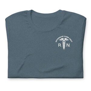 Folded heather slate ICU nurse shirt with white Intensive Care Unit RN design.