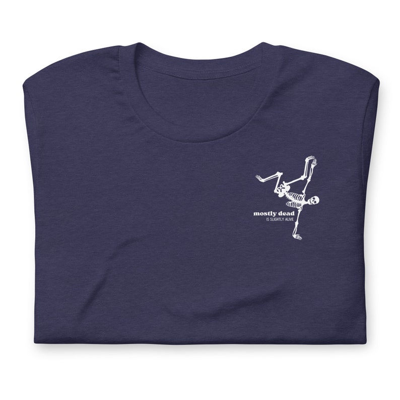 Puede incluir: Una camiseta azul marino con un gr&aacute;fico de esqueleto blanco haciendo una parada de manos. El texto "mostly dead is slightly alive" est&aacute; impreso debajo del esqueleto.