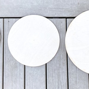 Peut inclure: Trois disques ronds en bois blanc de tailles diff&eacute;rentes. Les disques sont dispos&eacute;s du plus petit au plus grand, de gauche &agrave; droite. Le plus petit disque a deux petits trous au centre.
