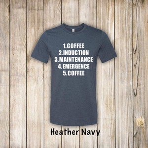 May include: A heather navy blue t-shirt with white text that reads "1. Coffee 2. Induction 3. Maintenance 4. Emergence 5. Coffee".
