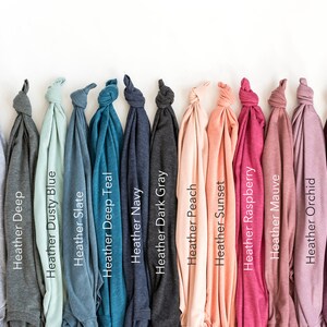 Puede incluir: Una fila de 15 camisetas dobladas en varios colores jaspeado, incluyendo ceniza, profundo, azul polvoriento, pizarra, azul teal profundo, azul marino, gris oscuro, melocot&oacute;n, puesta de sol, frambuesa, malva, orqu&iacute;dea, granate y cardenal.