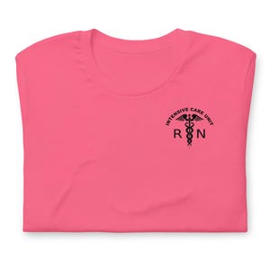 Folded bright pink ICU nurse shirt with black ICU RN left-chest graphic.