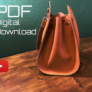 Peut inclure: Un sac en cuir brun avec une fermeture à cordon et une longue sangle. Le sac est posé sur une surface en bois. Le texte "PDF Téléchargement numérique" est visible dans le coin supérieur gauche de l'image.