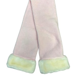 May include: A pale pink scarf with cream-coloured faux fur trim at each end. The scarf is made of a soft, plush material and is folded in half, creating a loop shape. The scarf is designed for warmth and style.