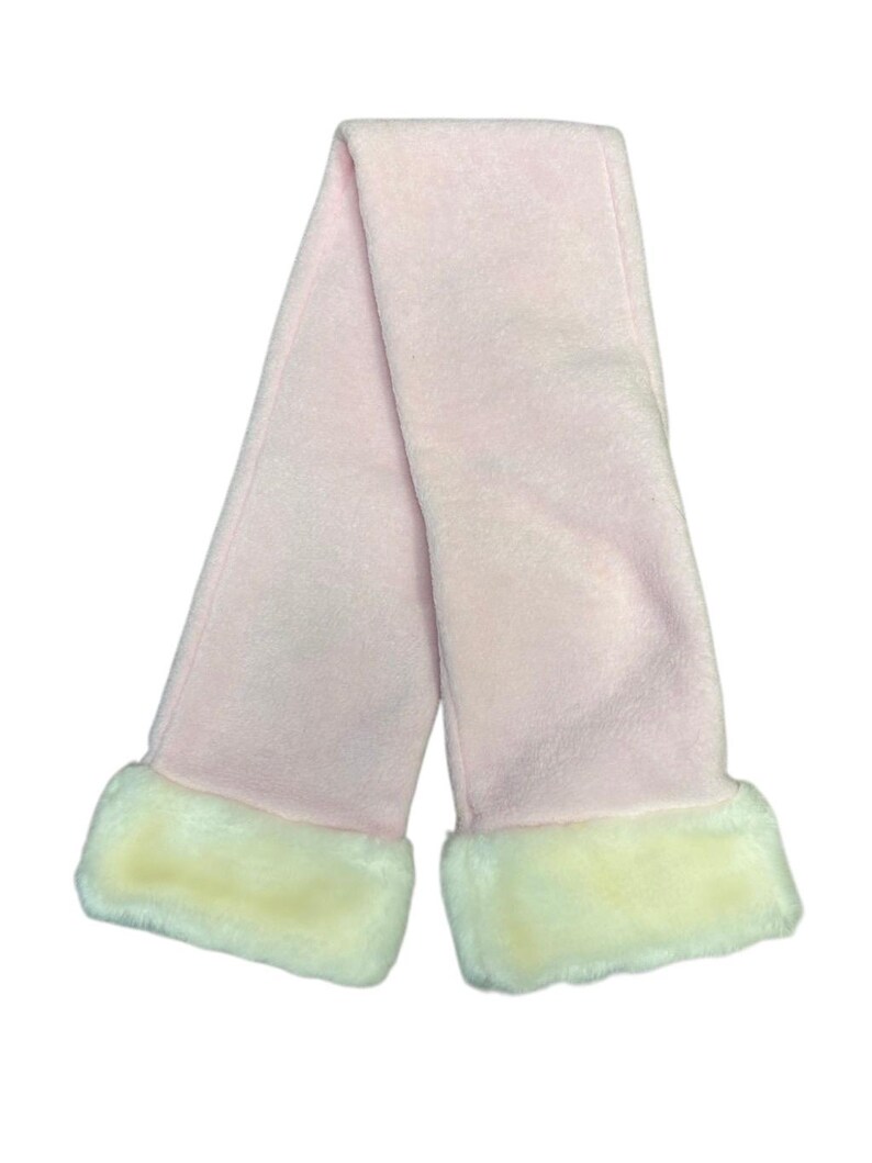 May include: A pale pink scarf with cream-coloured faux fur trim at each end. The scarf is made of a soft, plush material and is folded in half, creating a loop shape. The scarf is designed for warmth and style.