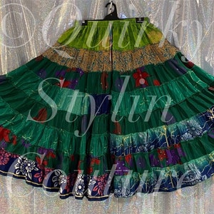 Puede incluir: Una falda de retazos multicolor con un esquema de colores verde, azul y rojo. La falda está hecha de varias telas y tiene un diseño con volantes. La falda está colgada de una percha.