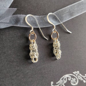 Orecchini pendenti in argento sterling in stile bizantino su un biglietto d'auguri stampato a mano e racchiuso in una busta bianca.