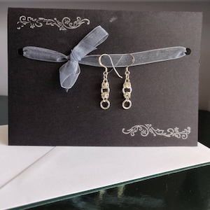 Orecchini pendenti in argento sterling in stile bizantino su un biglietto d'auguri stampato a mano e racchiuso in una busta bianca.