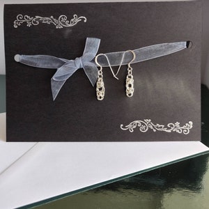 Orecchini pendenti in argento sterling in stile bizantino su un biglietto d'auguri stampato a mano e racchiuso in una busta bianca.