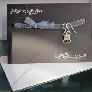 Orecchini pendenti in argento sterling in stile bizantino su un biglietto d'auguri stampato a mano e racchiuso in una busta bianca.