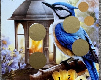 May include: A bluebird perched on a branch with a lantern behind it. The bird has gold circles on its body. The branch has a yellow flower with gold circles on it. The text "Magie des Frühlings" and "Würfeln" are visible. The text "45€" is also visible.