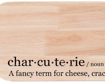 May include: A wooden chopping board with a handle, featuring the text "char-cu-te-rie / noun / shar koo ter ee A fancy term for cheese, crackers and stuff".