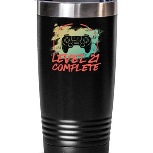 May include: Black stainless steel tumbler with a gamer-themed design. It features a red, yellow, and green video game controller graphic with the text "Level 21 Complete".