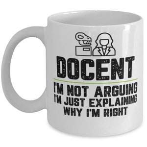 May include: White ceramic coffee mug with a black and white illustration of a person and a dinosaur skeleton. The text "DOCENT I'M NOT ARGUING I'M JUST EXPLAINING WHY I'M RIGHT" is printed on the mug.