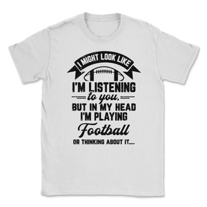 May include: White t-shirt with a black graphic that says "I might look like I'm listening to you, but in my head I'm playing Football or thinking about it..." with a football graphic above the text.