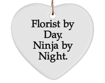 May include: White ceramic heart-shaped ornament with black text that reads "Florist by Day. Ninja by Night."