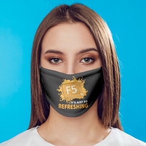 May include: A black face mask with the text "F5 IT'S JUST SO REFRESHING" in gold lettering. The mask is worn by a person with brown hair and a white shirt, against a blue background.