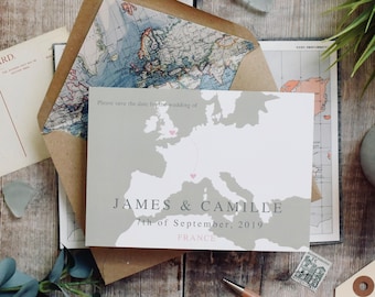 May include: A save-the-date card with a map design, featuring the names "JAMES & CAMILLE" and the date "7th of September, 2019, FRANCE." The card is light gray with a map of Europe and a pink heart marking a location.