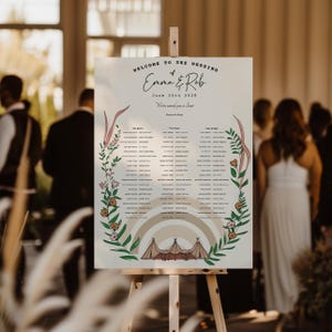 May include: A white wedding seating chart sign on a wooden easel featuring the text Welcome to the Wedding of Emma & Rob June 20th 2028. The design includes a central list of names, a beige rainbow graphic, and a tent illustration with floral vines.