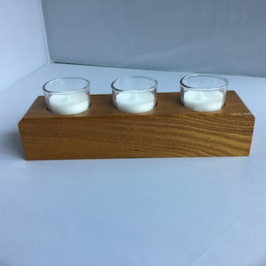 Peut inclure: Un bougeoir en bois avec trois bougeoirs en verre. Les bougeoirs sont remplis de bougies blanches.