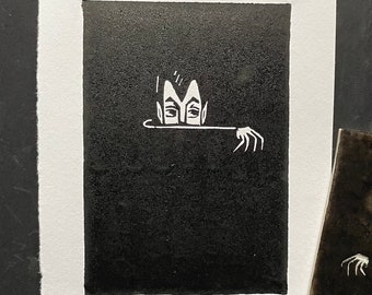 Pode incluir: Ilustração em preto e branco de uma criatura com duas faces que espreita por trás de uma superfície escura. A criatura tem uma cabeça em forma de coroa e olha para a direita.