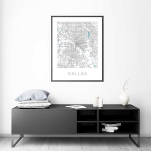 Pu&ograve; includere: Una stampa di mappa di Dallas, Texas in bianco e nero in una cornice nera appesa a una parete bianca sopra una consolle multimediale nera con due cassetti e tre ripiani. La consolle ha un cuscino bianco e due candele bianche in cima.