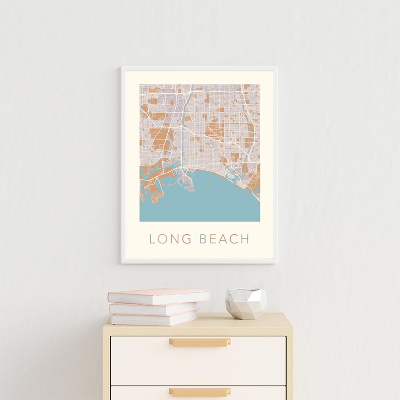 May include: A framed print of a map of Long Beach, California. The map is in shades of brown and blue, with the city streets and coastline outlined in white. The city name is printed in a light blue font at the bottom of the map.