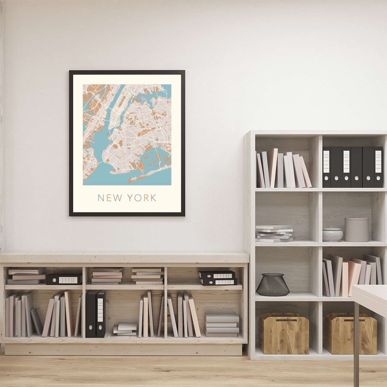 K&ouml;nnte beinhalten: Eine gerahmte Karte von New York City mit blauem Hintergrund und braunen Linien, die die Stra&szlig;en zeigen. Die Karte h&auml;ngt an einer wei&szlig;en Wand &uuml;ber einem Holzregal.