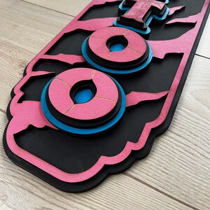 以下が含まれることがあります： ピンクとブルーのウッドサインに「Foo」という文字が重ねて書かれています。文字は重ねてあり、3D効果があります。