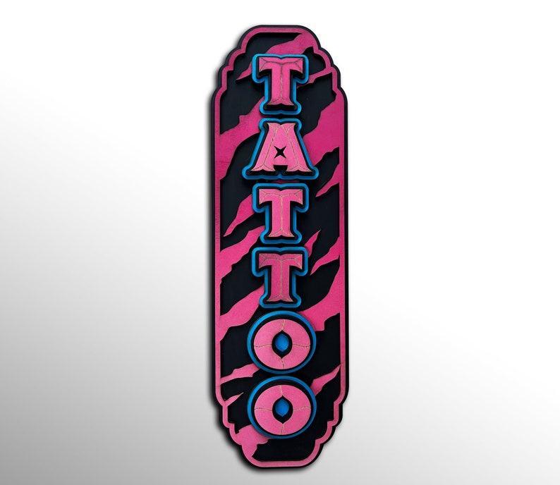 以下が含まれることがあります： ピンクと黒の看板に、青と白の文字で「TATTOO」と書かれています。看板には虎の縞模様があります。
