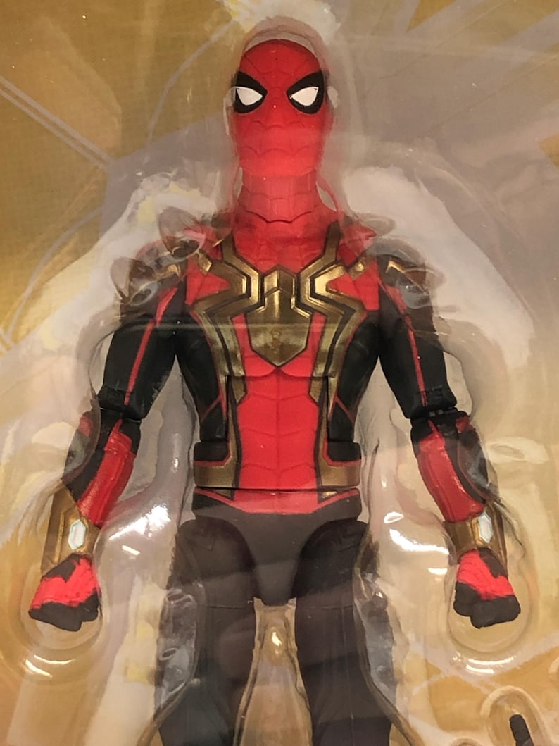 May include: A red and black action figure of Spider-Man wearing a gold and black suit. The figure has a detailed face with a red and black mask.
