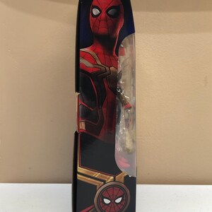 May include: A red and gold Spider-Man action figure in a box. The figure is wearing a red and gold suit with a black spider logo on the chest. The box has a picture of Spider-Man on the front.