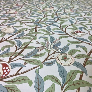 May include: A vintage wallpaper design featuring a repeating pattern of stylised trees, birds, and pomegranates. The wallpaper is cream-coloured with brown branches, green and blue leaves, and red and white pomegranates.