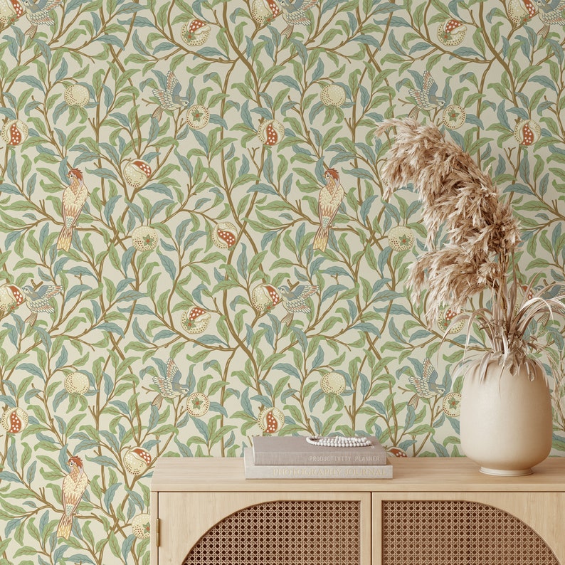 May include: A beige wallpaper with a repeating pattern of stylised birds, leaves, and pomegranates. The wallpaper is displayed on a wall behind a wooden cabinet with a woven rattan front.
